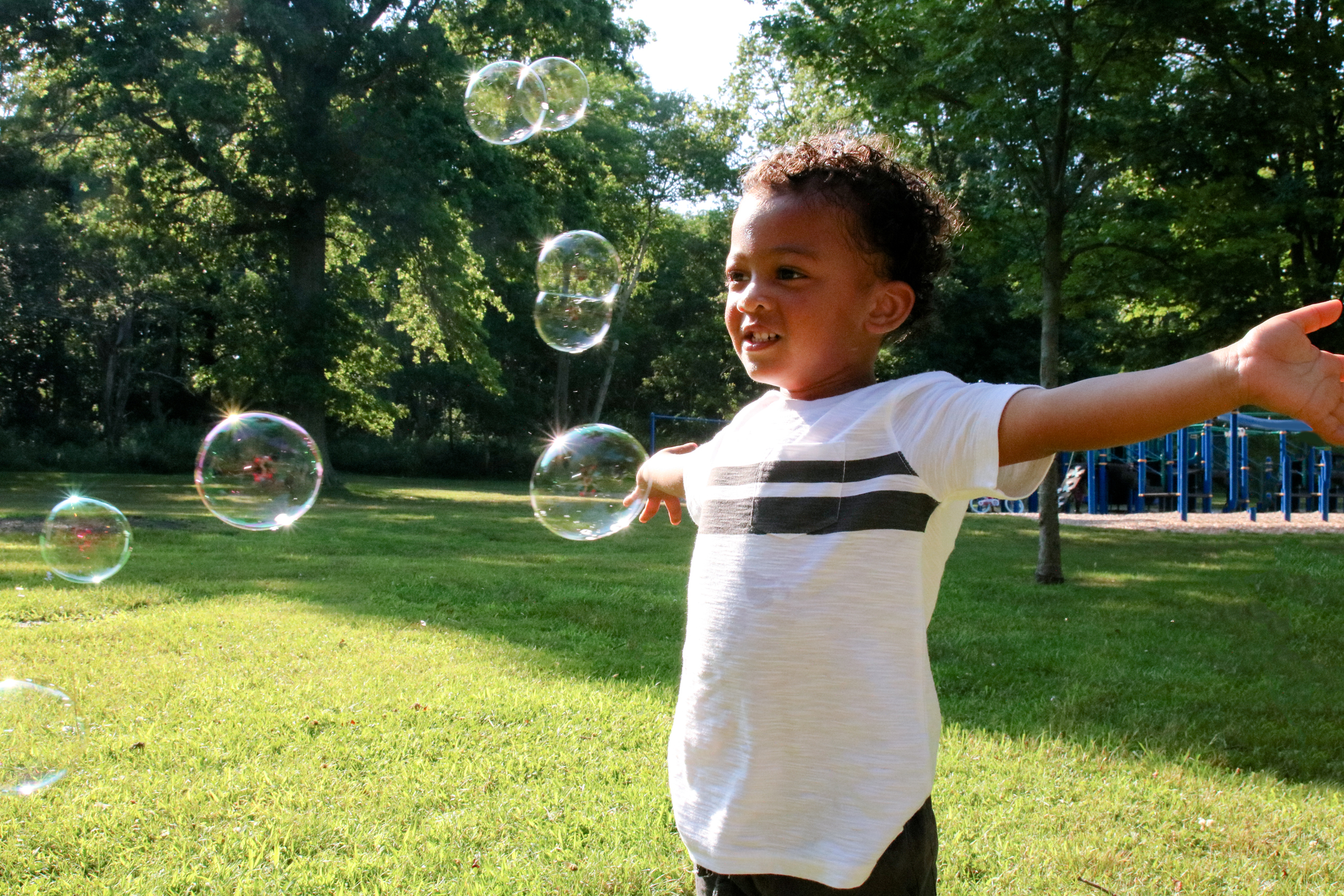 young boy arms outstretched bubbles